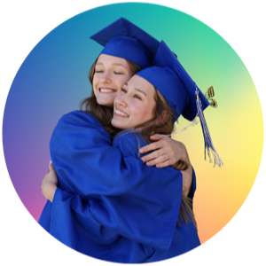 Two students in graduation regalia hugging in front of multi-colored background