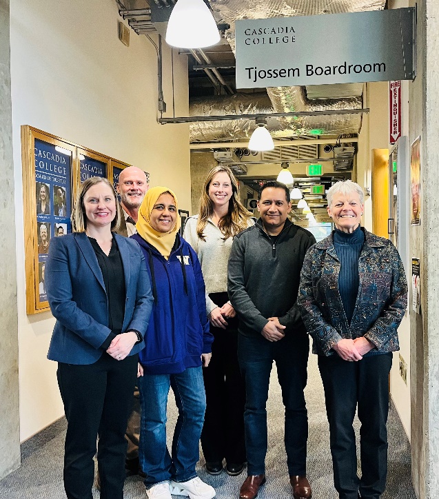 Trustee Meghan Quint, College President Eric Murray, Trustee Rania Hussein, Associate VP for Advancement Brittany Caldwell, Trustee Shahryar Qadri, and Trustee Colleen Ponto under the Tjossem Boardroom sign.