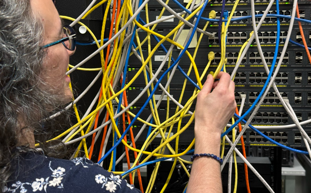 Student connecting computer servers with ethernet cable