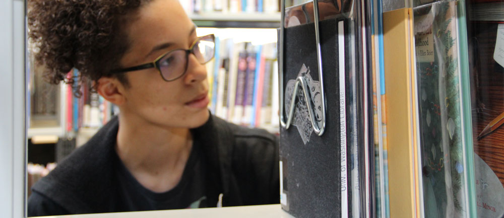 A student reading in front of a computer, demonstrating a focused and studious approach to online learning or research.