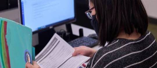 A student reading in front of a computer, demonstrating a focused and studious approach to online learning or research.