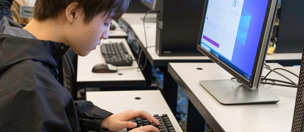 A student reading in front of a computer, demonstrating a focused and studious approach to online learning or research.