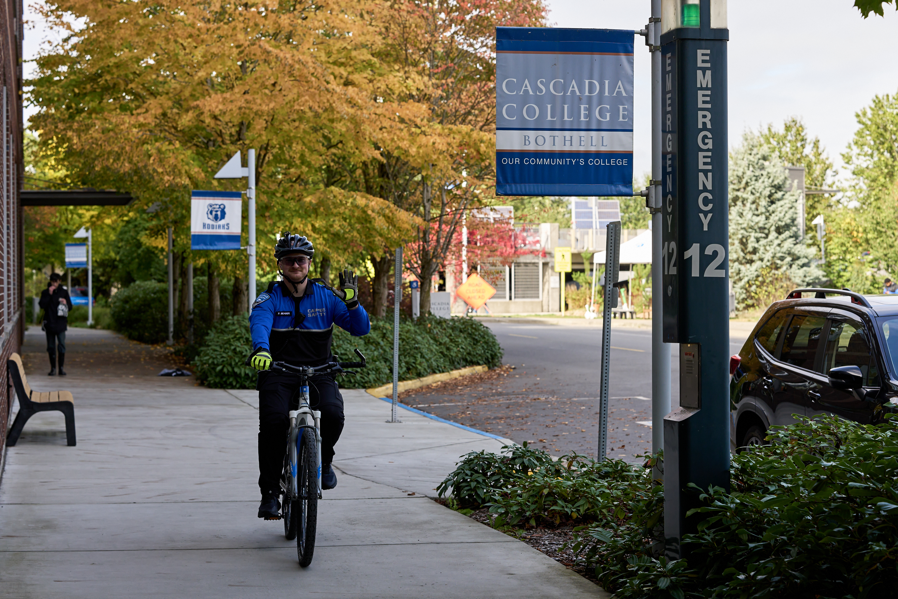campus employee biking on campus way with Cascadia banner in background