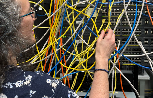 Student connecting computer servers with ethernet cable
