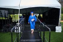 Cascadia College graduate in blue gown and cap walking out after collecting her diploma