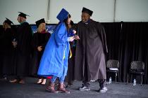 Board of Trustee member wishing a graduate as she collects her diploma on the graduation stage
