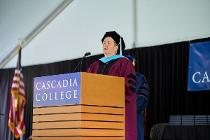 Cascadia College VP Dr. Kerry Levett in graduation garb speaking at podium