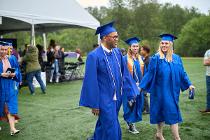 Cascadia College graduates in blue gowns and caps walking on the field after collecting their diploams