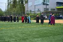 Faculty and board members lining up on the field in their graduation regalia