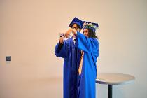 Two students in graduation gowns and hats taking a selfie