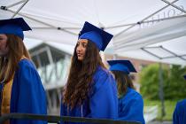 Three Cascadia College graduates in blue gowns and caps lining up to collect their diplomas