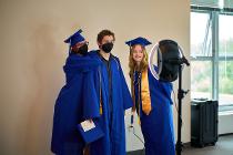 Three students in blue graduation garb in front of a selfie ring