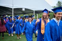 Cascadia College graduate in blue gowns and casp cheering and showing a thumbs up sign