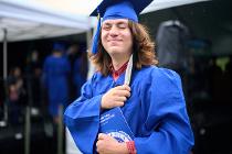 Cascadia College graduate in blue gown and cap winking at the camera