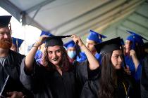 Cascadia College graduates in black gowns and caps; one student adjusting her cap