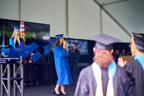 Graduate in blue gown on stage while others look on