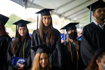 Cascadia College graduates in black gowns and caps standing up at the ceremony